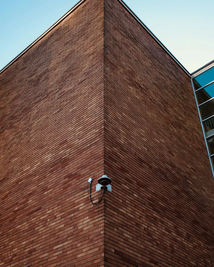 Surveillance camera mounted on the corner of a brick building